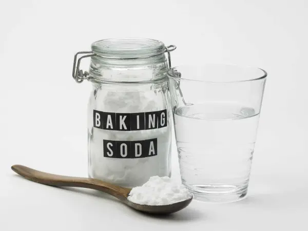 Hũ chứa baking soda, thìa gỗ và cốc nước.